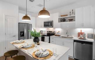 A modern kitchen with a white countertop and stainless steel appliances.
