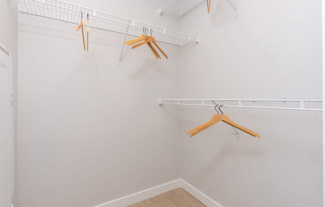 Three hangers are hanging on a white wall.