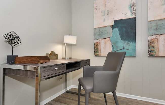 a desk with a chair and lamp in a room with paintings on the wall in The Oasis Daytona Apartment