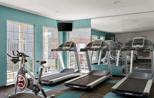 a gym with treadmills and exercise bikes in a room with windows at Verona, Littleton, CO, 80123