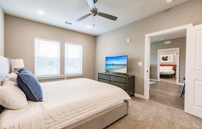 a bedroom with a bed, a tv, and two windows at Vantage Luxury Apartments in Cape Coral, FL