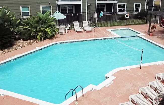 A small pool surrounded by chairs and plants.