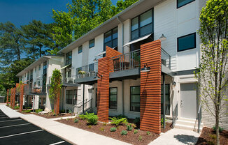 A row of modern townhouses with balconies and front yards.