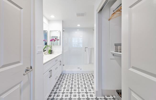 a white bathroom with a shower and a black and white tiled floor