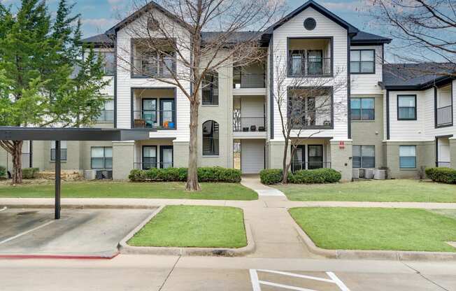 Apartment complex with a parking lot in front.