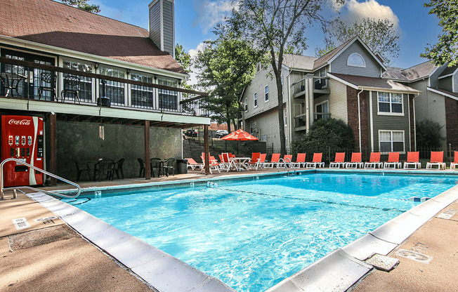 a swimming pool with chairs and a building in the background