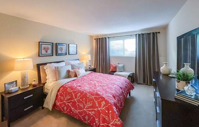 A bedroom with a red bedspread and a large bed.