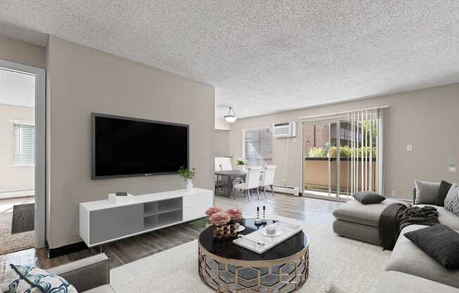 A modern living room with a flat screen TV, a white entertainment center, and a coffee table with a vase of flowers on it.