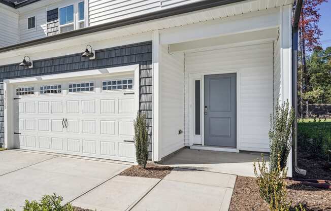 the front of a white house with a garage door