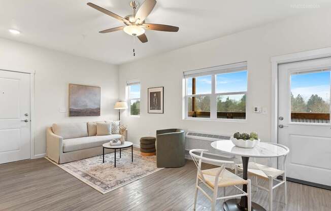A living room with a white couch, a white coffee table, and a ceiling fan.