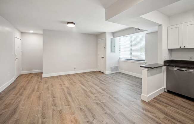 an empty kitchen and living room with wood flooring and a large window