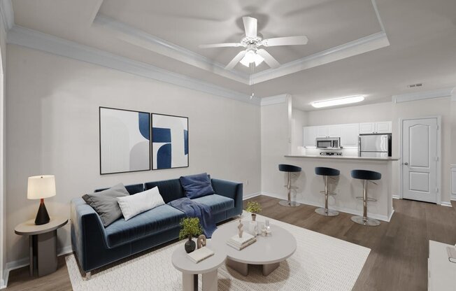 A living room with a blue couch, a white coffee table, and a painting on the wall.