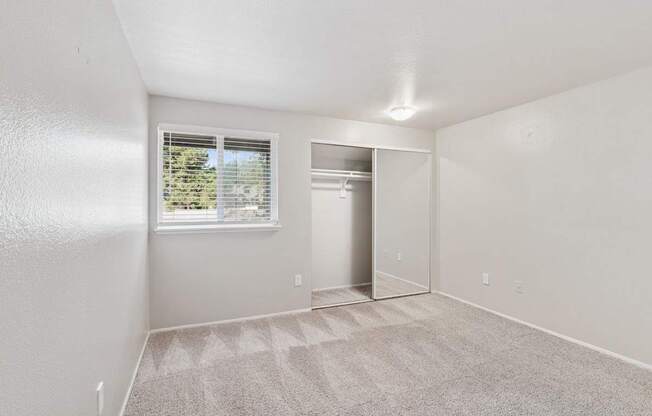 A room with a carpeted floor and a window with blinds.