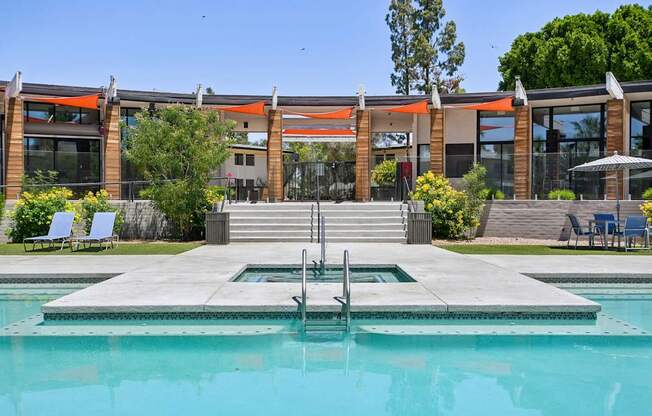 A swimming pool in front of a building with a glass facade.