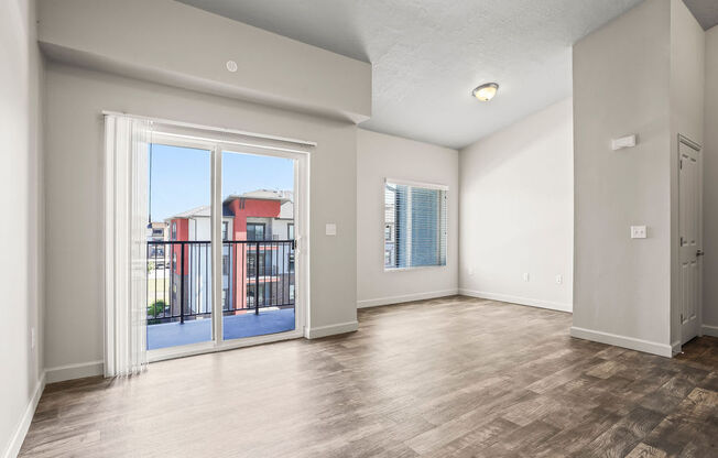 an empty living room with a sliding glass door to a balcony