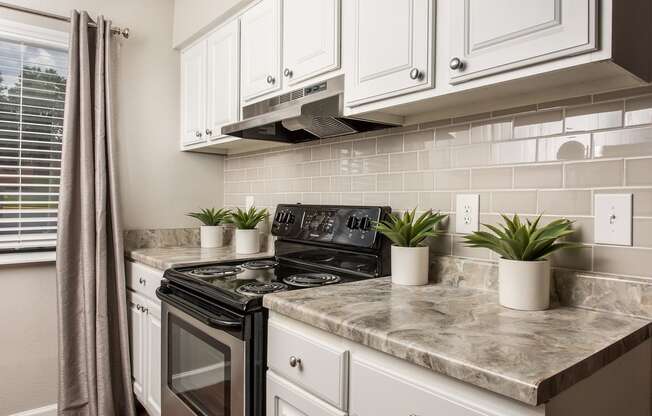 a kitchen with white cabinets and a black stove at Lodge of Overland Park Apartments, Overland Park , KS