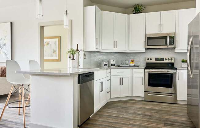 A modern kitchen with white cabinets and stainless steel appliances.