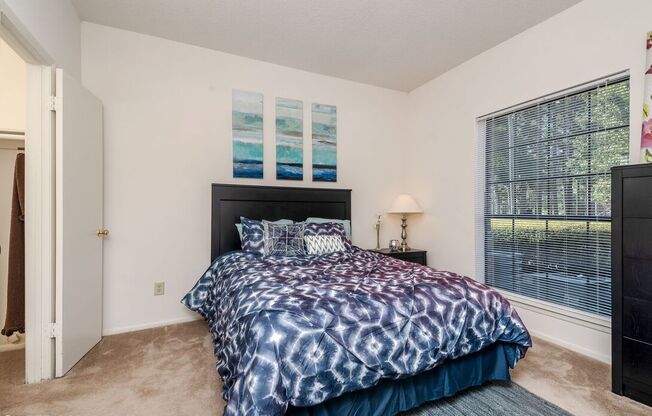 A bedroom with a bed, nightstand, and window.