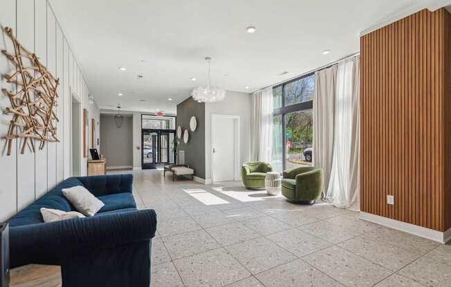 A spacious living room with a blue couch and a wooden wall.