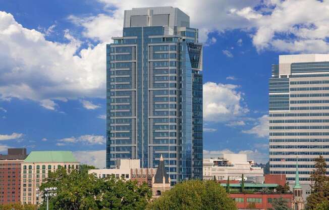 A tall building with a glass facade stands in front of a sky with clouds.