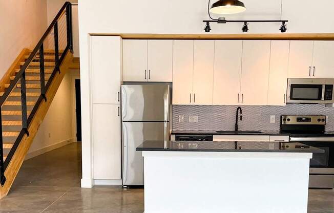 A kitchen with a staircase on the left side.