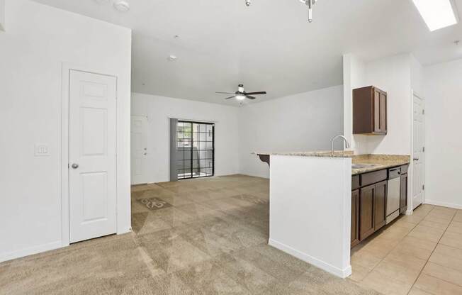 A spacious living room with a kitchen area in the background.