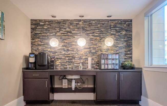 an office area with a desk and a coffee machine and a brick wall