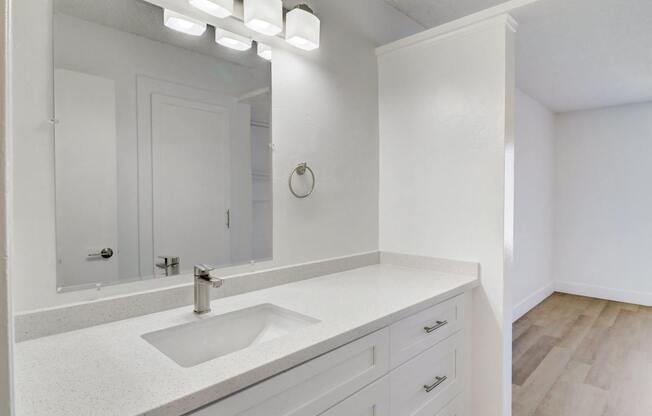 A white bathroom with a sink and mirror.
