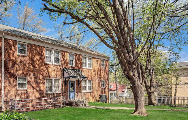 A red brick building with a tree in front at Highland Ridge Apartments, Maryland, 20743