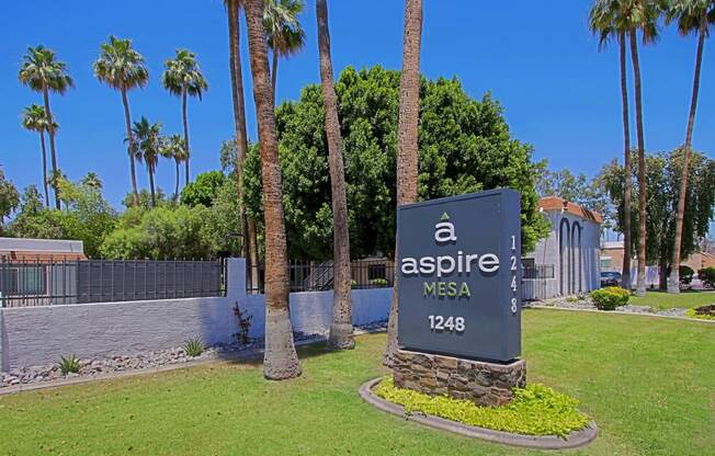 a sign for aspire west in front of a retaining wall and palm trees