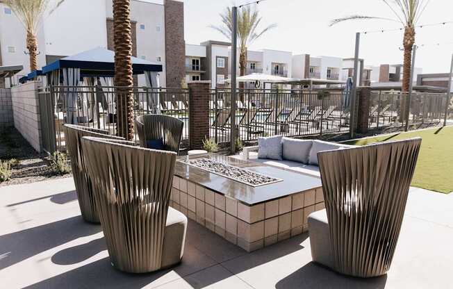 Two large chairs sit on a patio with a table between them.