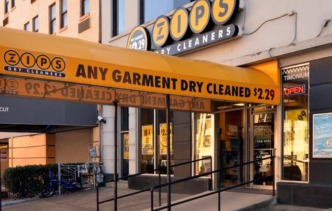 a store front of a building with a yellow sign that reads any garment dry cleaned