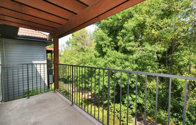 the balcony has a view of the yard and trees