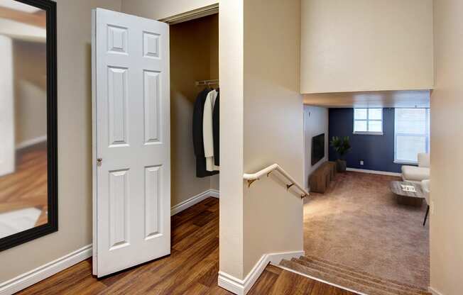 an open door leading into a living room with a mirror and a closet