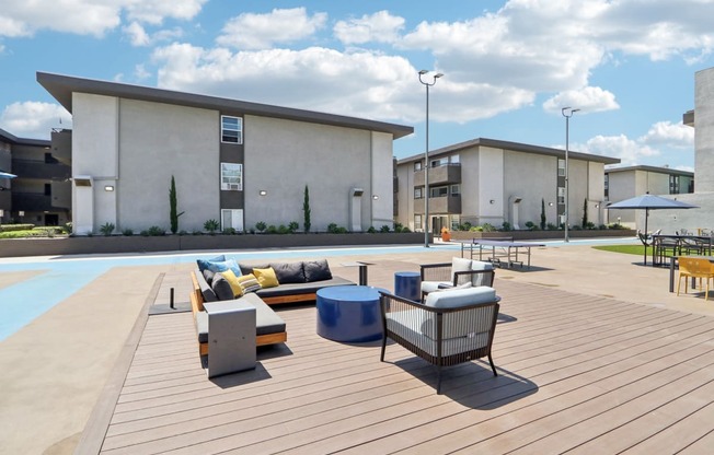 a rooftop patio with furniture and a pool in front of a building