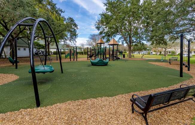 A playground with a green slide, a brown bench, and a yellowish ground.