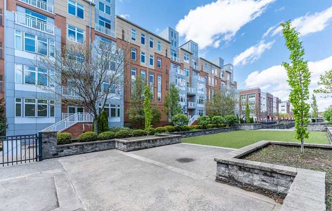 a courtyard with a grassy area and a large building in the background