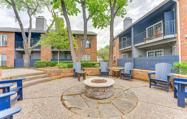 A courtyard with a fire pit surrounded by chairs and trees.