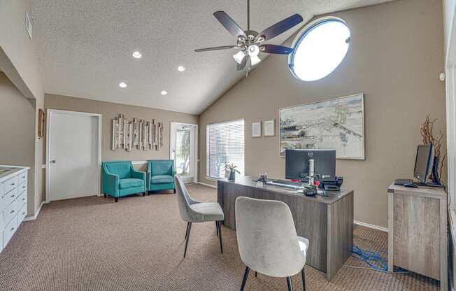 A room with a ceiling fan and a desk with a computer.