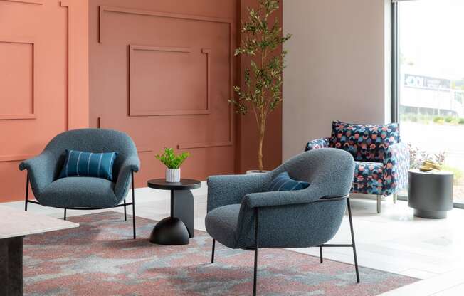 a living room with two blue chairs and a table at The Edison at Maple Grove, Minnesota