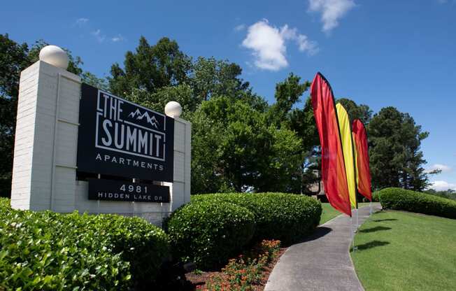 the sign for the summit apartments in front of a lawn with colorful umbrellas at The Summit Apartments, Tennessee