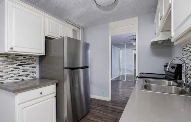 A kitchen with a stainless steel refrigerator and a sink.