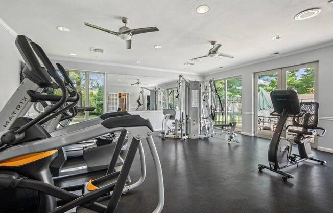 A spacious gym with a variety of exercise equipment and a ceiling fan.
