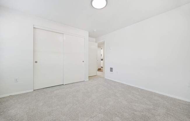 A white room with a carpeted floor and a white door.