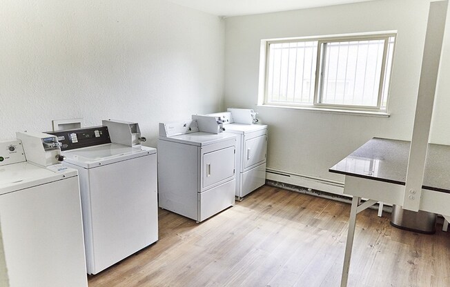 an empty room with washing machines and a table