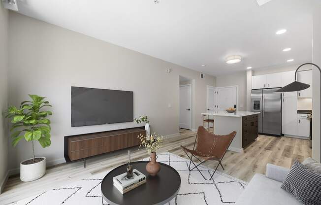 a living room with a tv on the wall and a kitchen in the background