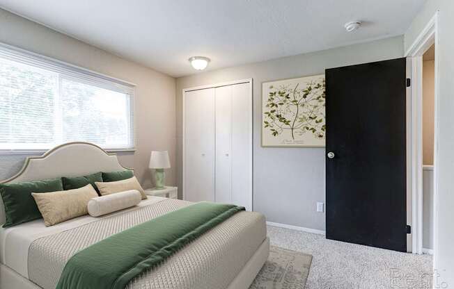 A bedroom with a bed, nightstand, and a painting on the wall.