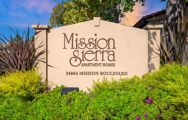 a sign formission sierra apartments sign in front of plants