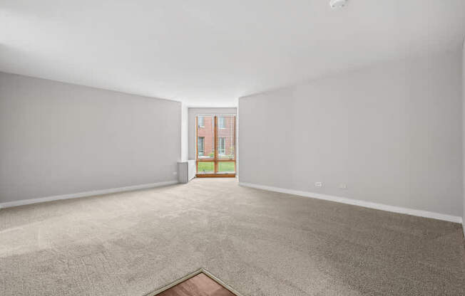 A room with a carpeted floor and a doorway leading to a balcony.