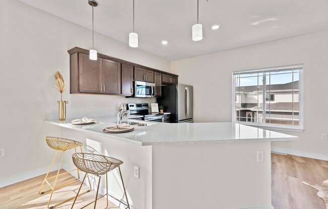 an open kitchen with a large island with bar stools at The Residences Apartments at Bear Tree | DeForest, WI, DeForest, WI 53532